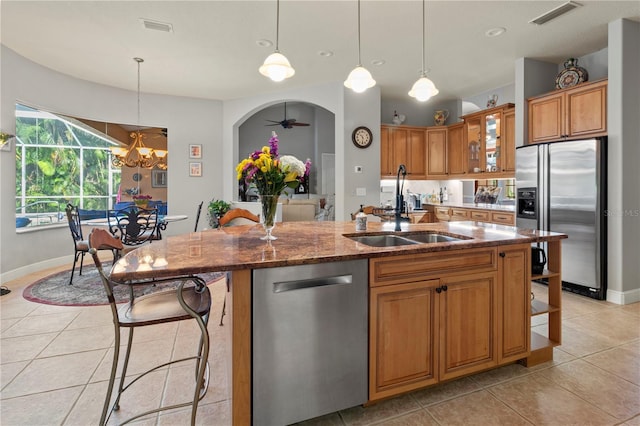 kitchen featuring arched walkways, stainless steel appliances, a sink, visible vents, and dark stone counters