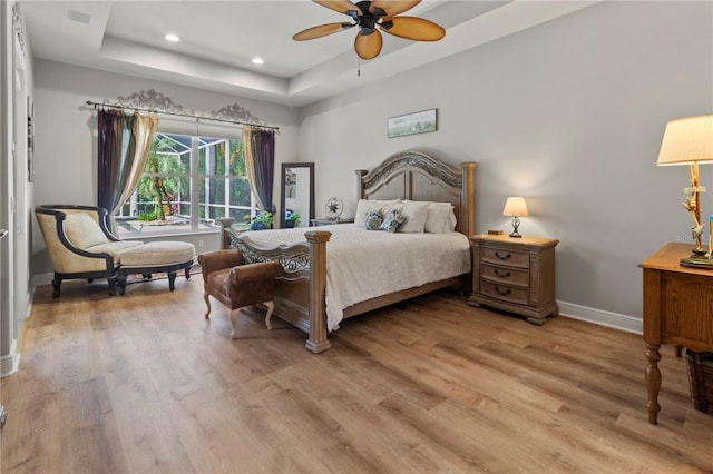 bedroom featuring recessed lighting, visible vents, baseboards, light wood finished floors, and a raised ceiling