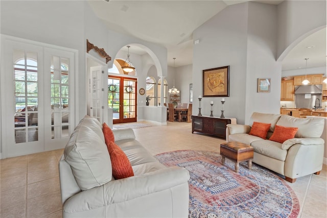 living room featuring french doors, light tile patterned flooring, and a towering ceiling