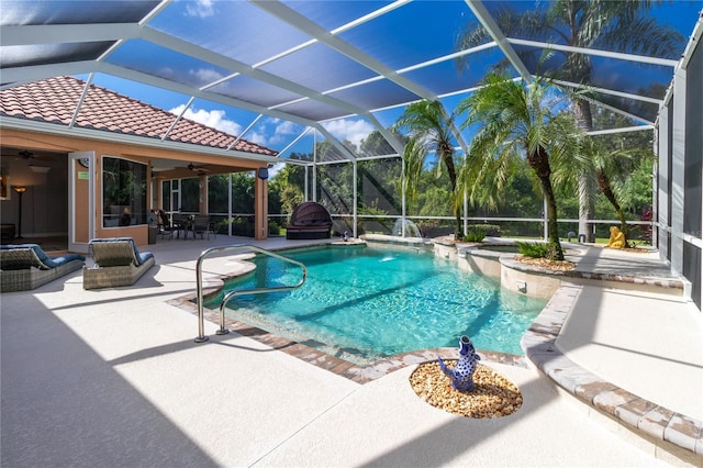 pool with a patio area, glass enclosure, and a ceiling fan