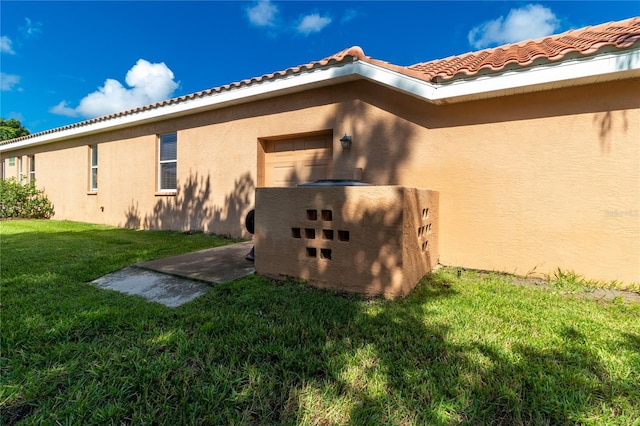 view of side of home featuring a yard, a tiled roof, and stucco siding