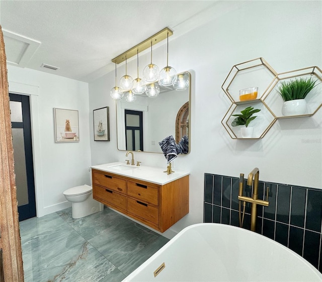 bathroom featuring a textured ceiling, vanity, toilet, and a washtub