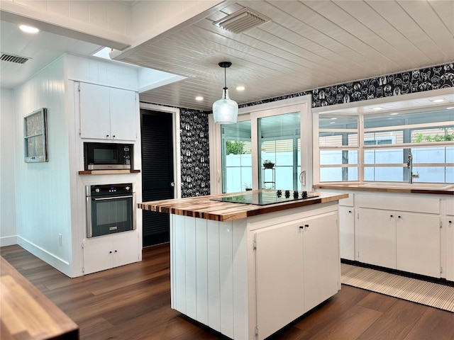 kitchen featuring dark wood-type flooring, wooden counters, appliances with stainless steel finishes, and white cabinets