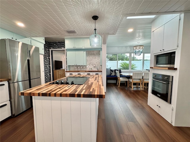 kitchen with wood counters, an inviting chandelier, a center island, dark hardwood / wood-style floors, and appliances with stainless steel finishes