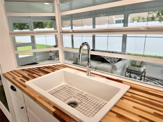 kitchen featuring hardwood / wood-style flooring, sink, wood counters, and white cabinetry