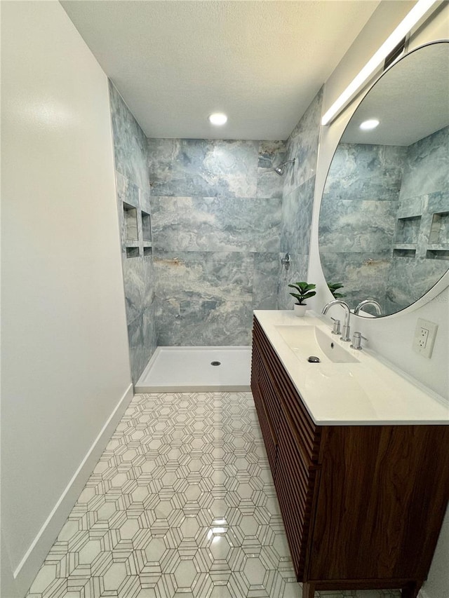 bathroom featuring a tile shower, a textured ceiling, and vanity