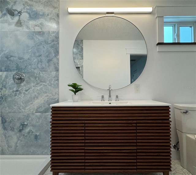 bathroom featuring tiled shower, toilet, and vanity