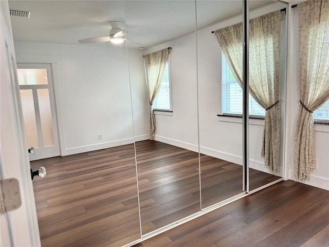 unfurnished bedroom with dark wood-type flooring, a closet, and ceiling fan