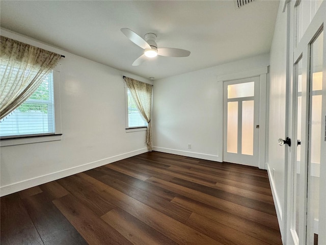 empty room featuring a wealth of natural light, ceiling fan, and dark hardwood / wood-style floors