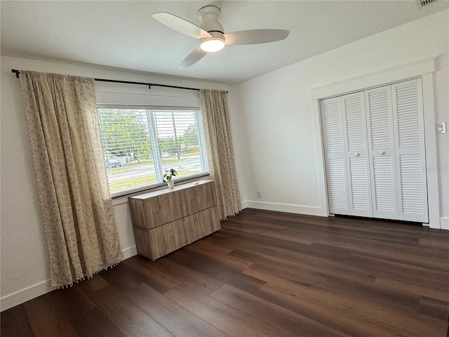 unfurnished bedroom with dark wood-type flooring, ceiling fan, and a closet