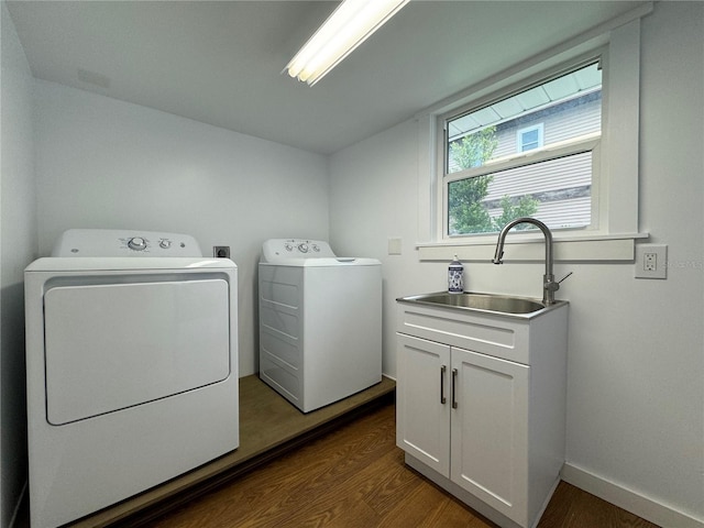 clothes washing area featuring washing machine and clothes dryer, cabinets, sink, and hardwood / wood-style flooring