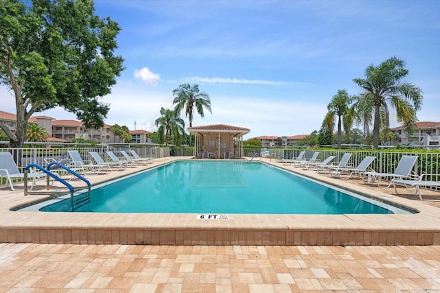 community pool with a patio area and fence