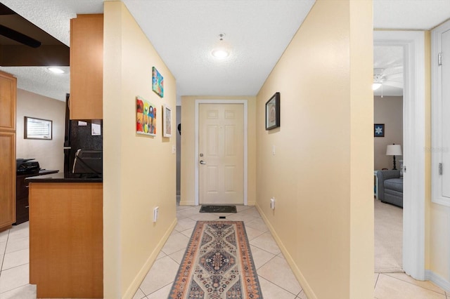 hallway with lofted ceiling, light tile patterned floors, and a textured ceiling