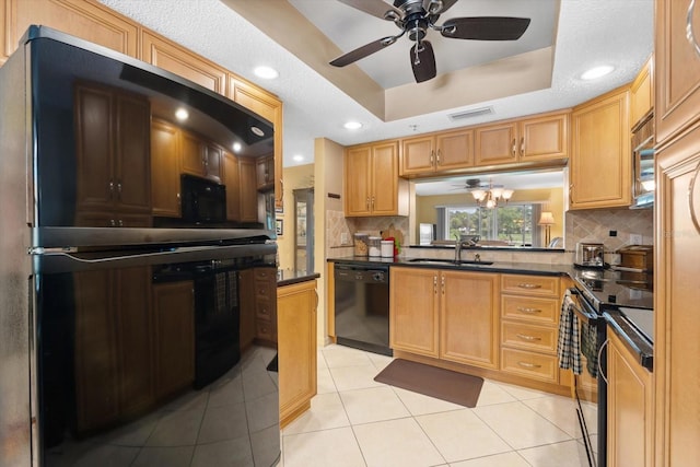 kitchen featuring a raised ceiling, dishwasher, dark countertops, stainless steel range with electric cooktop, and fridge