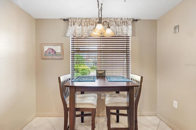 dining space featuring a textured ceiling, light tile patterned floors, and baseboards