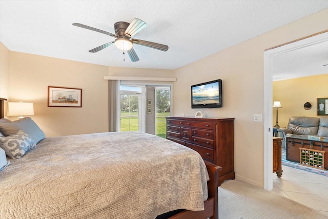 bedroom featuring light carpet, light tile patterned floors, a ceiling fan, access to exterior, and a textured ceiling