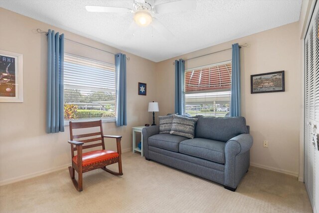 living room with ceiling fan, light colored carpet, a healthy amount of sunlight, and a textured ceiling