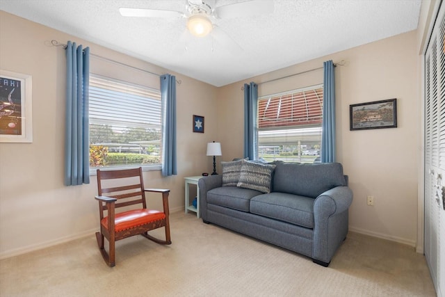 sitting room with light carpet, ceiling fan, a textured ceiling, and baseboards