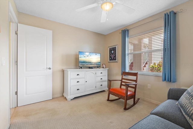 sitting room with a textured ceiling, ceiling fan, baseboards, and light colored carpet