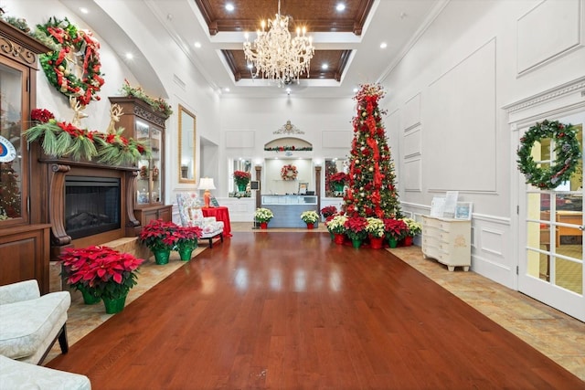 interior space featuring a decorative wall, a high ceiling, a high end fireplace, an inviting chandelier, and crown molding