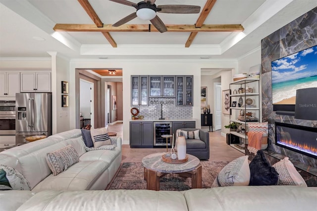 living room featuring wine cooler, beamed ceiling, crown molding, bar area, and ceiling fan