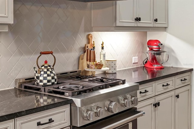 kitchen with white cabinets, stainless steel range, and decorative backsplash