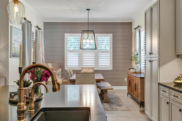 dining area featuring ornamental molding, wood walls, sink, and an inviting chandelier