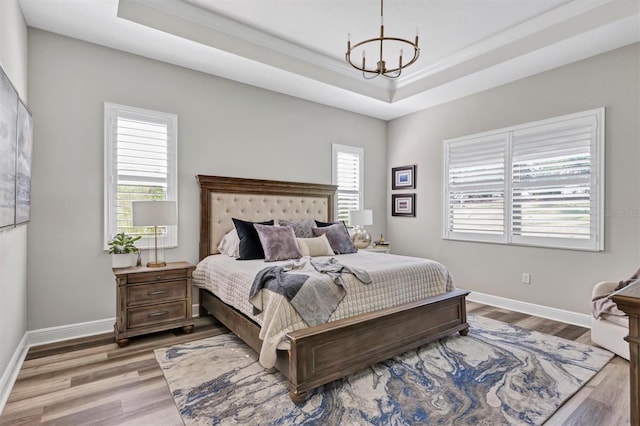 bedroom featuring hardwood / wood-style floors, a raised ceiling, and a notable chandelier