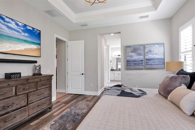 bedroom with crown molding, ensuite bath, a tray ceiling, and dark hardwood / wood-style flooring