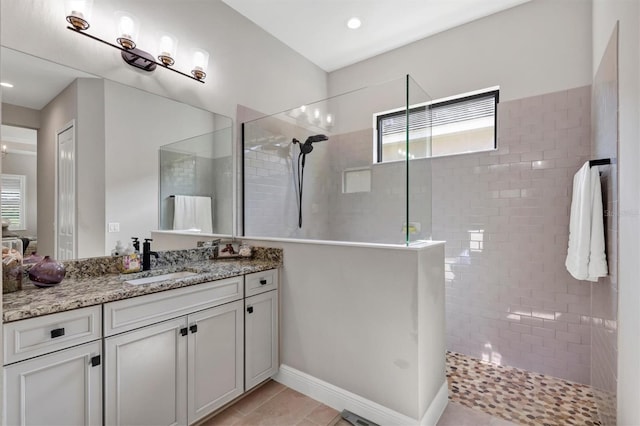 bathroom with vanity, tiled shower, and tile patterned flooring