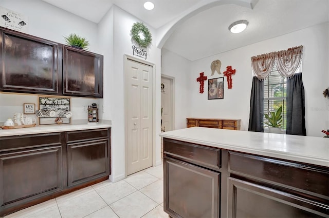 kitchen featuring light tile patterned floors and dark brown cabinets