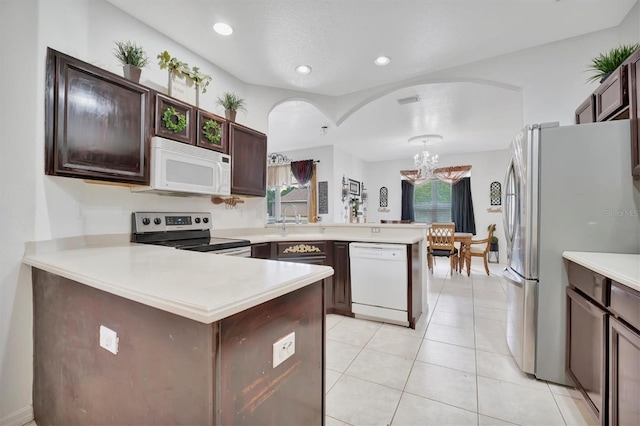 kitchen featuring sink, dark brown cabinetry, white appliances, light tile patterned floors, and kitchen peninsula