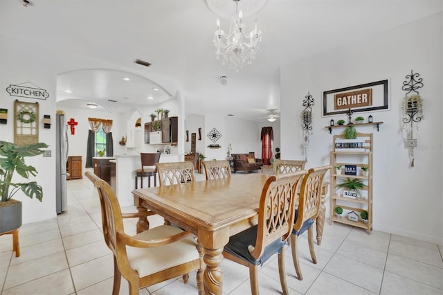 tiled dining room featuring ceiling fan with notable chandelier