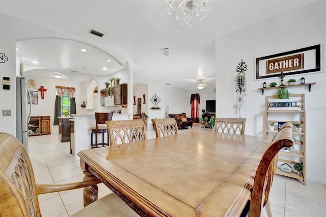 tiled dining area featuring ceiling fan with notable chandelier