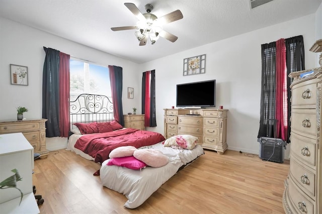 bedroom featuring ceiling fan, light hardwood / wood-style floors, and a textured ceiling