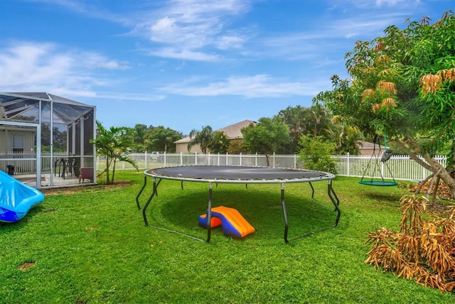 view of yard featuring a patio area, glass enclosure, and a trampoline