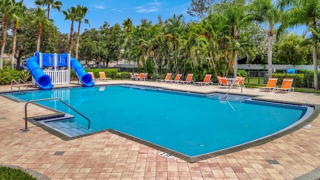 view of swimming pool with a patio, a water slide, and a playground