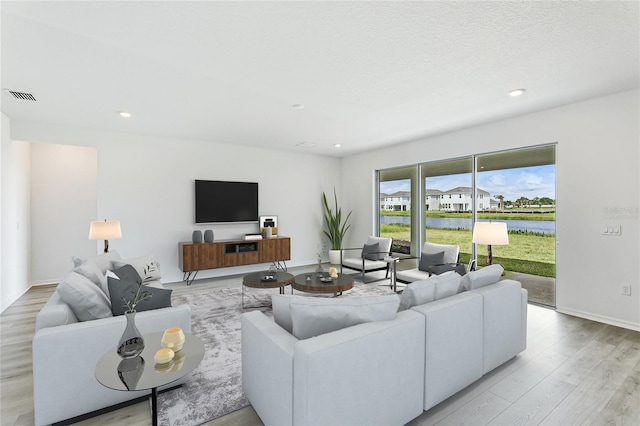 living room featuring light wood-style floors, baseboards, visible vents, and recessed lighting