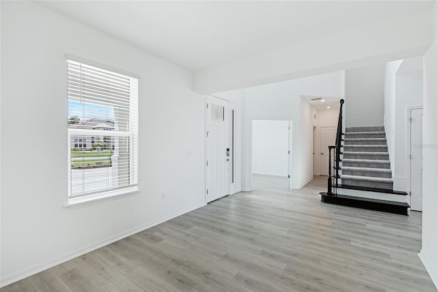 interior space with light wood-type flooring, baseboards, and stairs