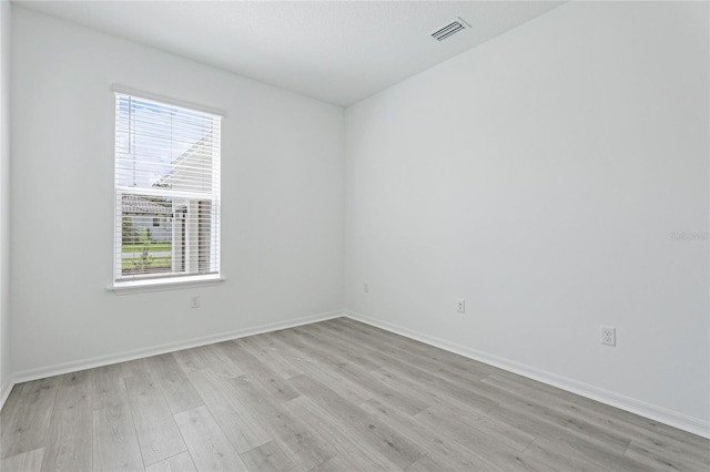 unfurnished room with baseboards, visible vents, and light wood finished floors