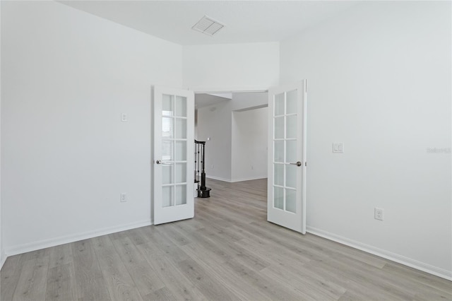 spare room with french doors, light wood-style flooring, visible vents, and baseboards