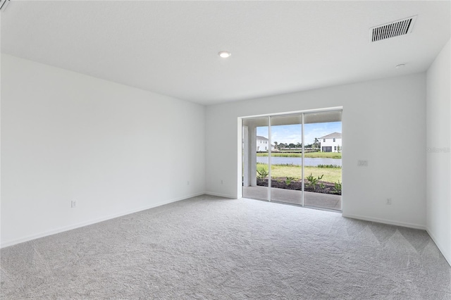 spare room with carpet, visible vents, and baseboards