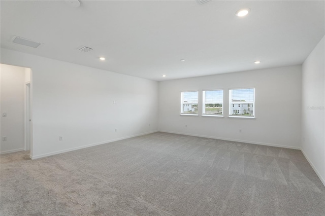 empty room with recessed lighting, light colored carpet, visible vents, and baseboards