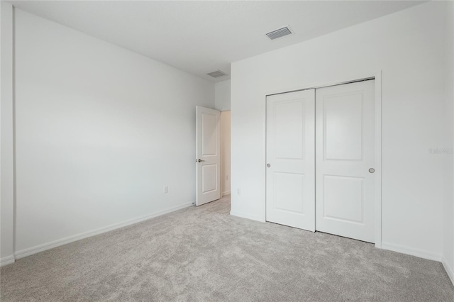 unfurnished bedroom with light colored carpet, a closet, visible vents, and baseboards