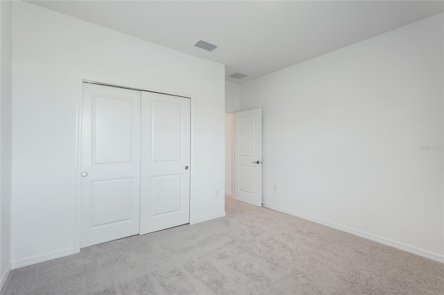 unfurnished bedroom featuring carpet, a closet, visible vents, and baseboards