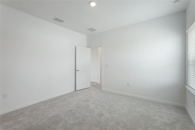 carpeted spare room featuring visible vents and baseboards