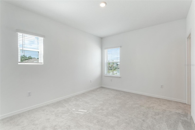 unfurnished room featuring light carpet and baseboards