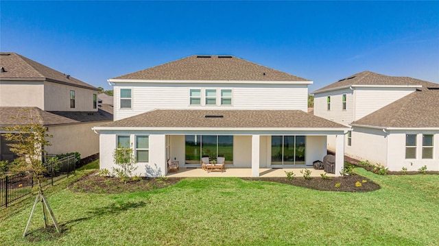 rear view of property featuring a shingled roof, fence, a lawn, and a patio