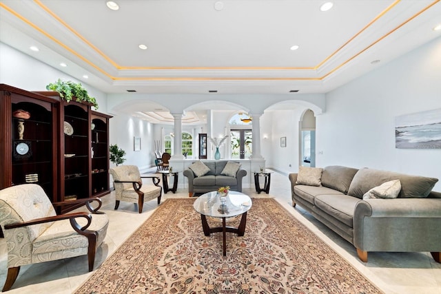 living room featuring a tray ceiling, ornate columns, ornamental molding, and light tile patterned flooring