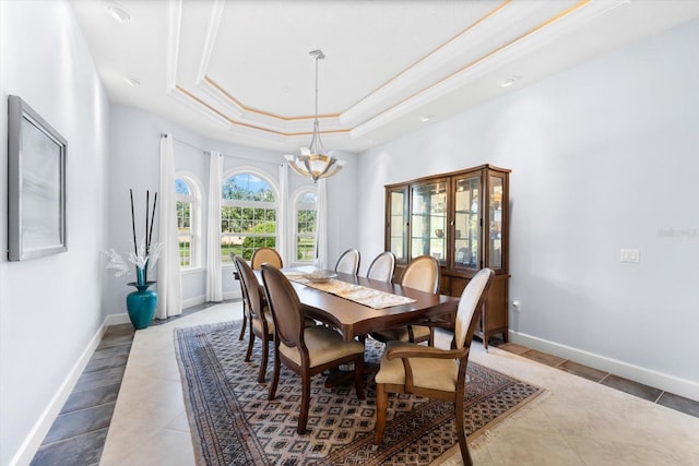 tiled dining area featuring an inviting chandelier, a raised ceiling, and crown molding